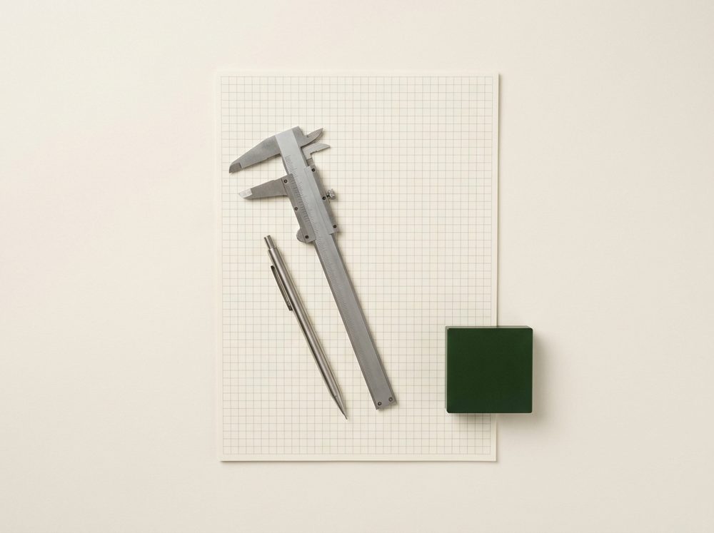 Calipers and a pencil resting on a blank sheet of grid paper.